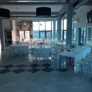 a dining room with white tables and chairs and windows at Hollywood Motel in Podlugovi