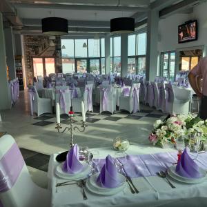 una habitación llena de mesas blancas y sillas con servilletas púrpuras en Hollywood Motel, en Podlugovi
