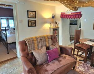 a living room with a brown couch with pillows at Beebole Cottage in Askrigg