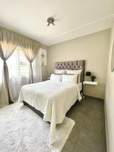 Un dormitorio con una cama grande y una ventana en Central and peaceful 2-bedroom Apt #ZonaHomes, en Midrand