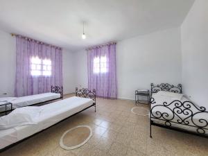 a bedroom with two beds and two windows at Yassmine in Djerba