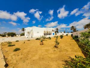 a large white building with trees in a field at Yassmine in Djerba