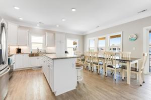 a kitchen with white cabinets and a table and chairs at Glimmering Shell Hideaway in Holden Beach