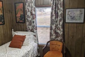 a bedroom with a bed and a chair and a window at Lake Mac Retreat, boating, fishing hunting. in Lewellen