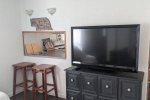 a flat screen tv sitting on a cabinet with two stools at Lake Mac Retreat, boating, fishing hunting. in Lewellen