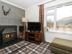 a living room with a television and a fireplace at Ben Grianan in Aberfeldy