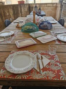 uma mesa de madeira com pratos e utensílios em Bed and breakfast "Selena" with swim pool em Nadur