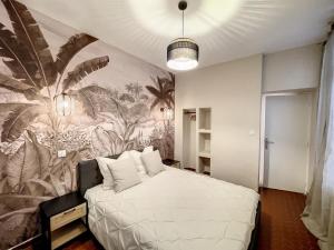 a bedroom with a large white bed with a tropical mural at VIEUX NICE - LE COSY - 5 min des PLAGES - WIFI - PARKING PUBLIC in Nice