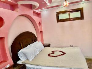 ein Schlafzimmer mit einem Bett in einem rosa Zimmer in der Unterkunft Pyramids hills view apartment in Kairo