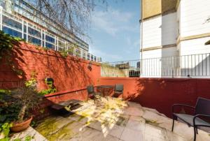 a patio with tables and chairs in front of a building at 4 Bedrooms Villa, Hugh Street Central London in London