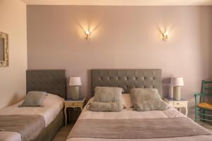 1 dormitorio con 2 camas y 2 lámparas en la pared en Hôtel La Bastide des Monges, en Nyons