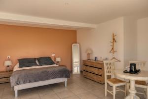 - une chambre avec un lit, une table et une commode dans l'établissement Hôtel La Bastide des Monges, à Nyons