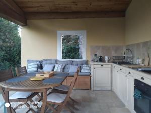 a kitchen and living room with a table and a couch at Proche Uzès petit gîte avec grande cuisine d'été et piscine in Saint-Siffret +12 photos