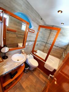 een badkamer met een wastafel, een toilet en een spiegel bij Casa Ocean Pier in Puerto Ayora