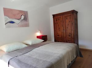 1 dormitorio con 1 cama y armario de madera en Haus am Brunnen en Prato allo Stelvio