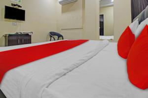 een bed met rode en witte kussens en een tv bij OYO Flagship 81091 Hotel Ozn Stays in Nagpur
