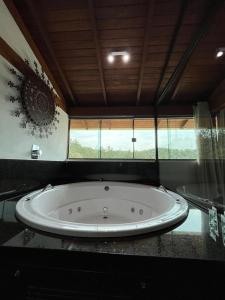 La salle de bains est pourvue d'une grande baignoire et d'une fenêtre. dans l'établissement Pousada Mar Mineiro Macacos, à Nova Lima