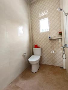 een badkamer met een toilet, een raam en een douche bij Villa Cisarua KB Isyana in Brujul