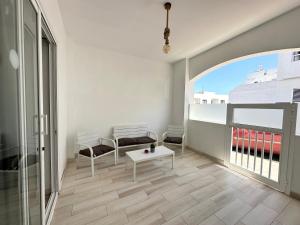 a living room with two benches and a table at Cotillo Luna en centro, 1 min de la playa, cocina completa y WIFI in Cotillo