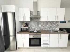 a kitchen with white cabinets and a stainless steel refrigerator at Cotillo Luna en centro, 1 min de la playa, cocina completa y WIFI in Cotillo