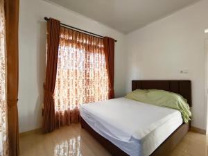 een slaapkamer met een bed en een groot raam bij Villa Cisarua KB Isyana in Brujul