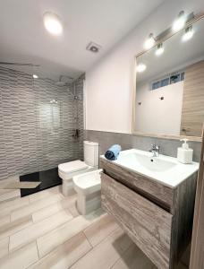 a bathroom with a sink and a toilet and a mirror at Cotillo Luna en centro, 1 min de la playa, cocina completa y WIFI in Cotillo