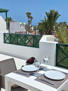 una mesa blanca con 2 copas de vino en el balcón en SunnyDaze en Tías