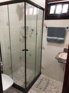 a glass shower in a bathroom with a sink at Suíte Trilha do Sol 2 in Arraial do Cabo
