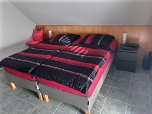 1 cama con edredón rojo y negro en una habitación en Ferienwohnung Bell im Brohltal, en Niederdürenbach