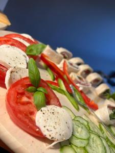 a plate of food with tomatoes and cheese and vegetables at Villa Ventana 2 City Free Parking Śniadanie w cenie 503 18 18 11 in Poznań