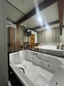 - une grande baignoire dans une chambre avec un lit dans l'établissement Pousada Mar Mineiro Macacos, à Nova Lima