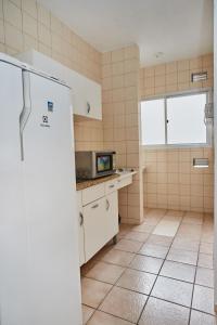 a kitchen with a white refrigerator and a window at Monte Libano Apart Hotel in Florianópolis