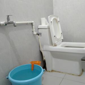a bathroom with a toilet and a blue bucket at Traveler House in Dimāpur