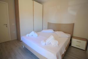 a bedroom with a white bed with towels on it at Beachfront Sion Sarande Apartment 2 in Sarandë