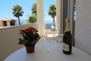 a bottle of wine and two glasses on a table at Beachfront Sion Sarande Apartment 2 in Sarandë