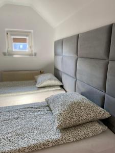 a bedroom with a bed with a headboard and two pillows at Apartment Storczykowa Airport in Gdańsk
