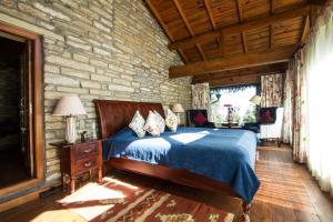 a bedroom with a bed and a stone wall at Nine Furlongs, Binsar Wildlife Sanctuary in Almora