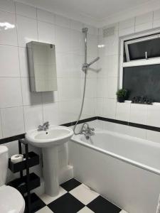 a bathroom with a sink and a tub and a toilet at 1 Bedroom Home With Free Parking & Private Garden in London