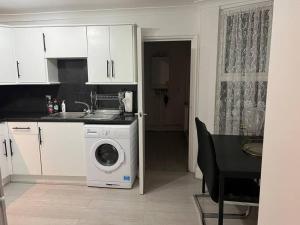 a kitchen with a washing machine next to a table at 1 Bedroom Home With Free Parking & Private Garden in London