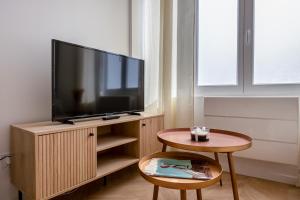 a living room with a flat screen tv on a wooden cabinet at La Perle Citadine En Hyper Centre in La Rochelle