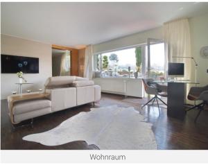 een woonkamer met een witte bank en een tafel bij Beste Lage in Bochum Sehr hochwertige, individuelle Wohnung als Hotelalternative mit Südterrasse, PKW-Stellplatz, Wallbox u.v.m. in Bochum