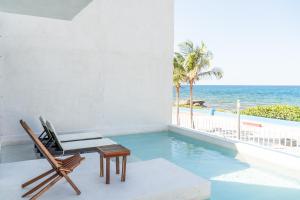 Cette chambre dispose d'une piscine, d'une chaise et d'une vue sur l'océan. dans l'établissement Villa Saadhu with fantastic oceanview, à Isla Mujeres