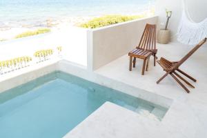 a patio with a pool and chairs and the ocean at Villa Saadhu with fantastic oceanview in Isla Mujeres