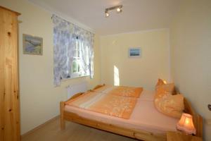 ein Schlafzimmer mit einem Bett mit orangefarbener Bettwäsche und einem Fenster in der Unterkunft Ferienwohnungen 300 m zum Strand in Glowe