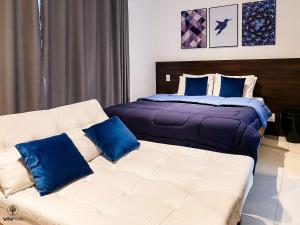 um quarto com uma cama e um sofá com almofadas azuis em Sweet Home - Vivare Augusta em São Paulo