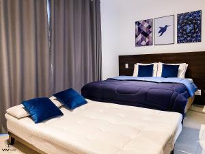 two beds with blue pillows in a bedroom at Sweet Home - Vivare Augusta in Sao Paulo