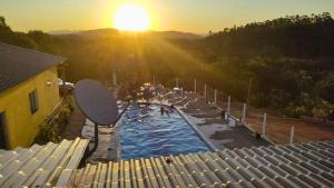 een uitzicht op een zwembad bij zonsondergang bij Lindo chalé no alto da colina, vista paradisíaca do por do sol, proximo a praia e cachoeiras in Pariqueraçu