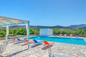 a swimming pool with chairs and a table at Hotel Smaragdi Apartments in Finikas