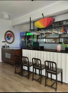 eine Bar mit 3 Stühlen und einer Theke mit einem bunten Regenschirm in der Unterkunft Toskana otel restorant in Şarköy