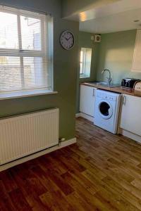 a kitchen with a washing machine and a clock on the wall at Cosy Cottage, Nr Betws y Coed. in Llanrwst